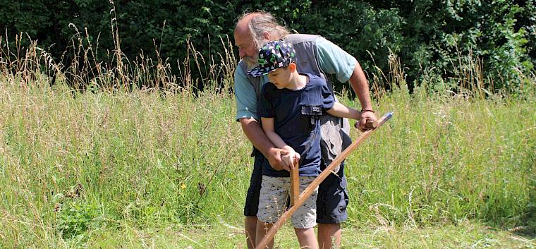 Das Sensenmähen mit Heinz Peikert von Stepping Woods machte den Schüler*innen besonders viel Spaß. © LPV/F. Hohn Kinde beim Sensenmähen