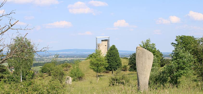 Offene Landschaft mit Natur und Skulpturen.