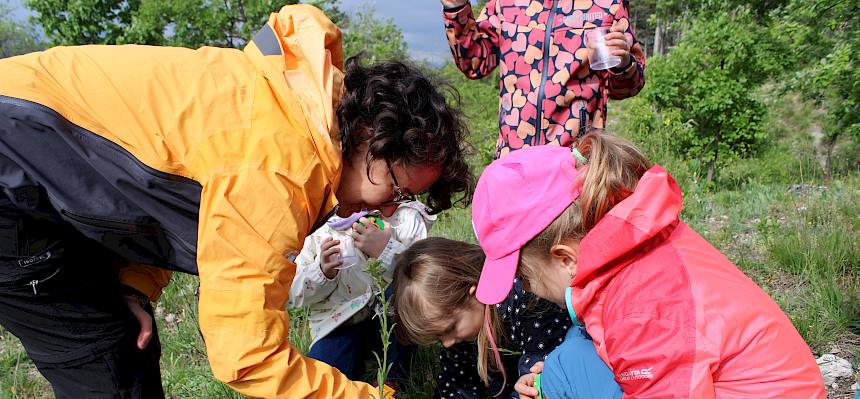 Naturpädagogin hilft Kindern mit Becherlupen