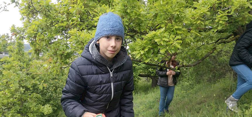 Schüler mit Becherlupe und Smartphone