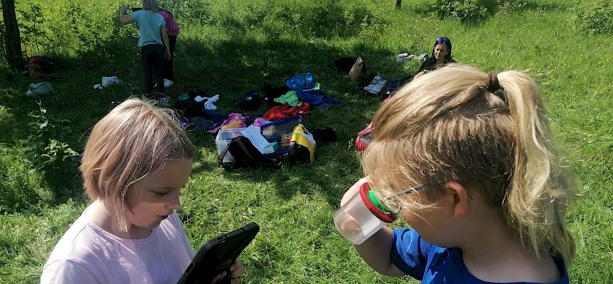 Schüler:innen mit Tablet und Becherlupen