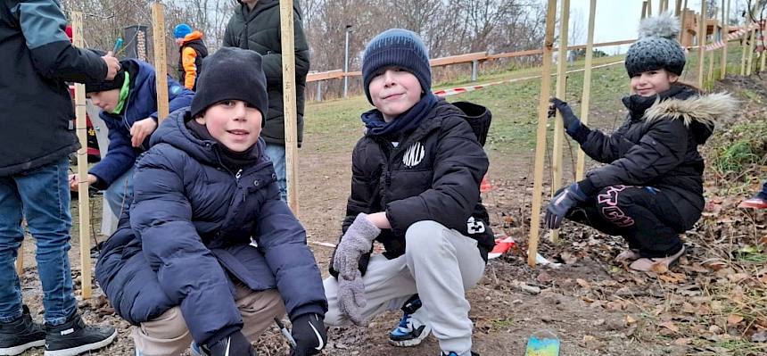 Kinder beim Pflanzen eines Strauches