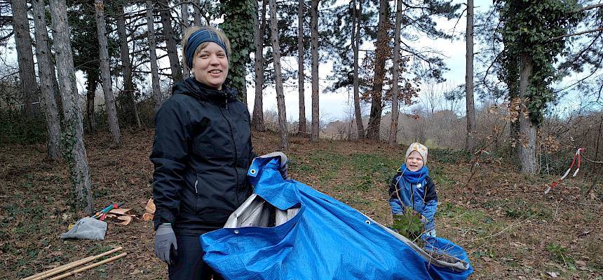 Mutter und Kind tragen Plane mit Schnittgut