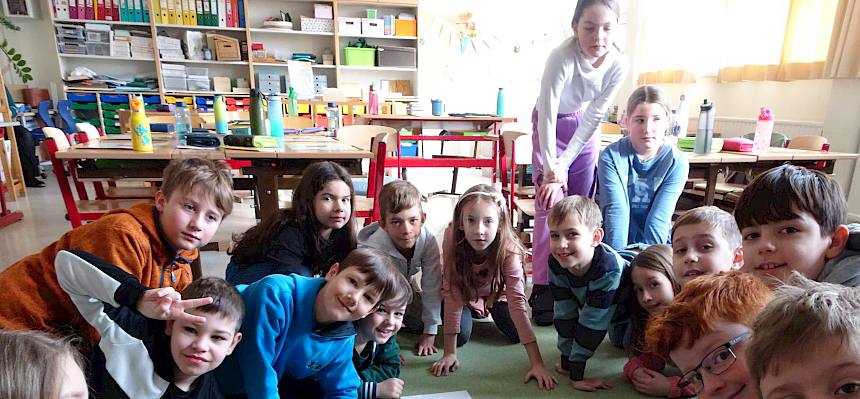 Kinder sitzen im Kreis am Boden
