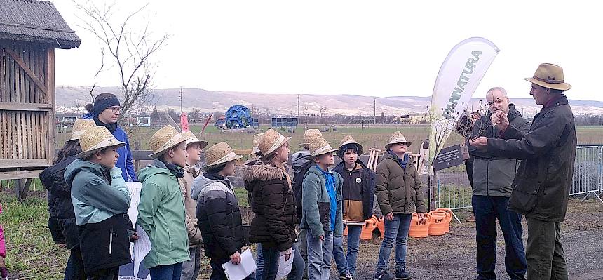 Kinder stehen im Kreis und hören Biologen zu