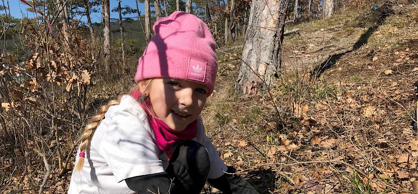 Kind sitzt am Waldboden.