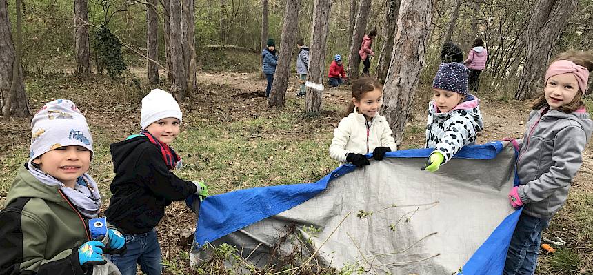 Kinder tragen Plane mit Schnittgut