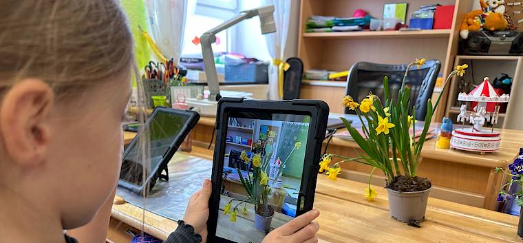 Anhand mitgebrachter Pflanzen konnte geübt werden, wie man mit dem Tablet ein gutes Foto für die Bestimmung macht. © LPV/E. Weisz-Emesz Kind fotografiert Blume mit Tablet