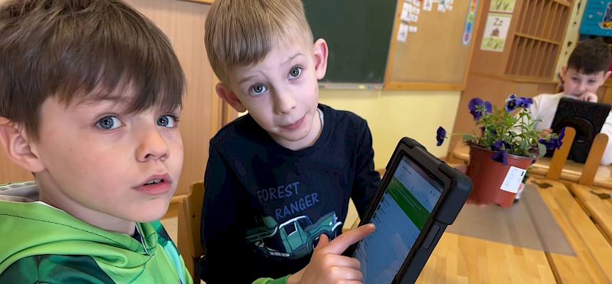 Kind zeigt auf Tablet