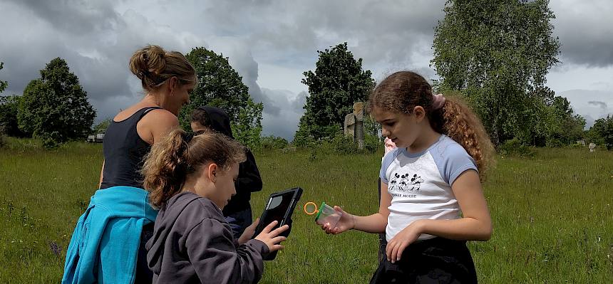Kinder mit Tablet und Becherlupe