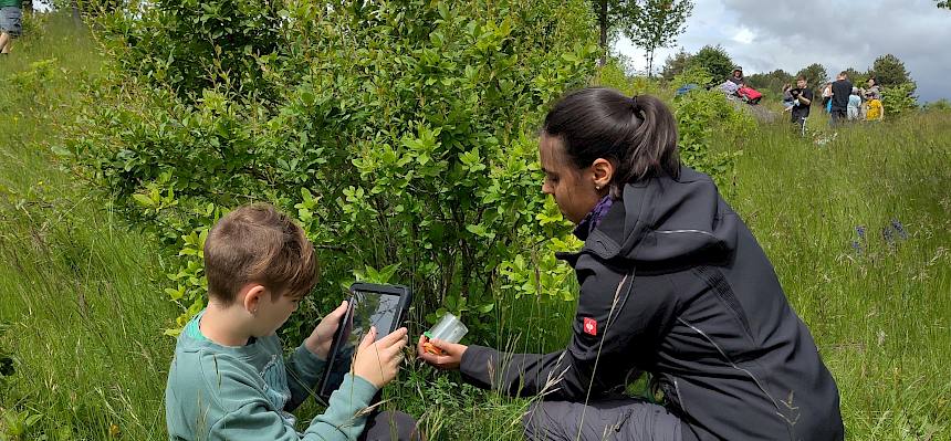FRau und Kind mit Tablet und Becherlupe