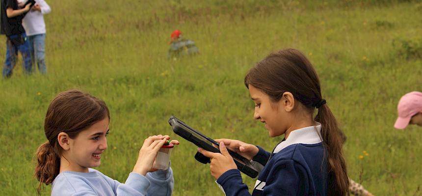 Kinder mit Tablet und Becherlupe