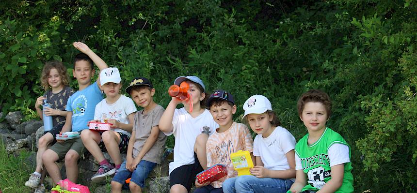Schüler:innen Jausnen auf Mauer sitzend