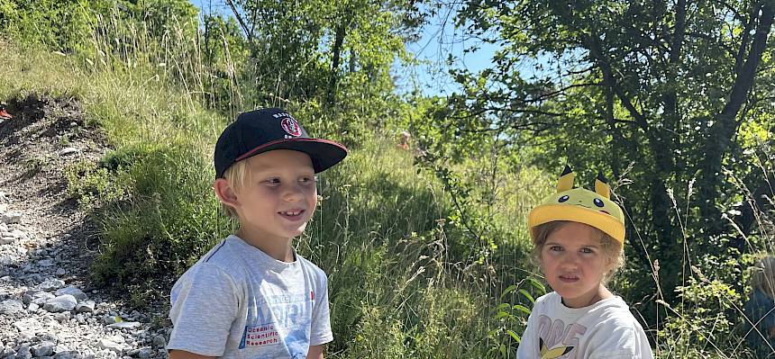 Kinder sitzen am Boden mit Mohnblume