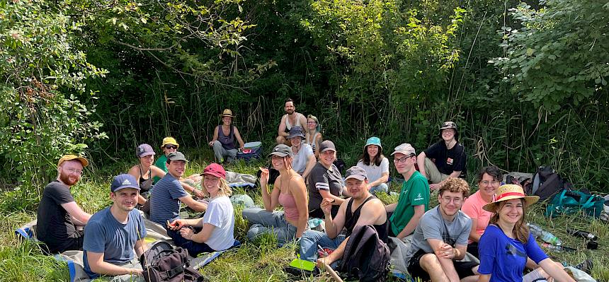 Menschen sitzen auf Wiese bei Jause