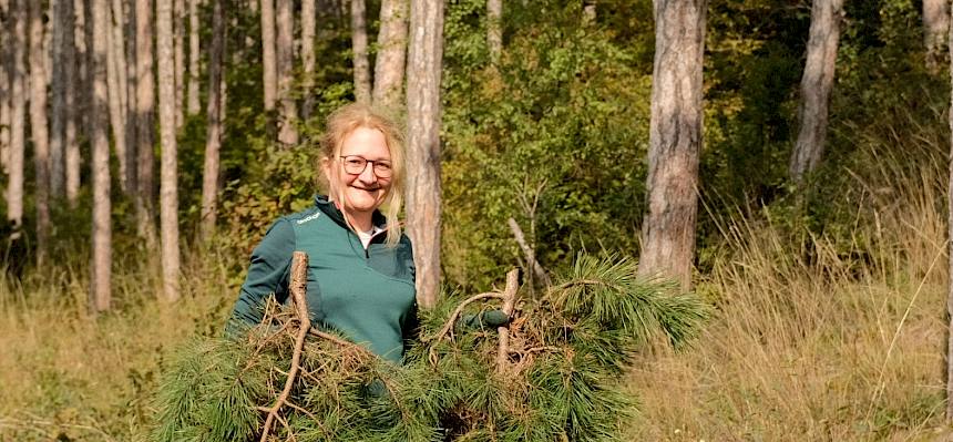 Frau mit Föhrenästen