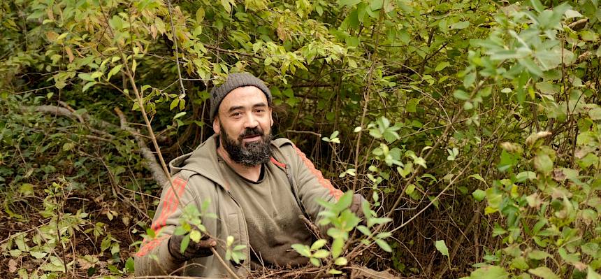 Mann sitzt am Boden im Wald