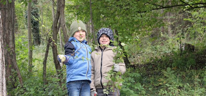 Kinder präsentieren ein abgeschnittenes Gehölz