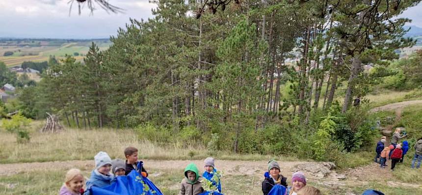 Kinder tragen eine Plane mit Schnittgut