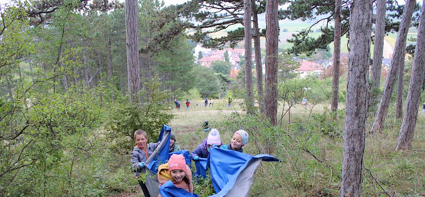 Kinder tragen Plane mit Schnittgut