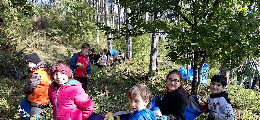 Kinder tragen eine Plane mit Schnittgut