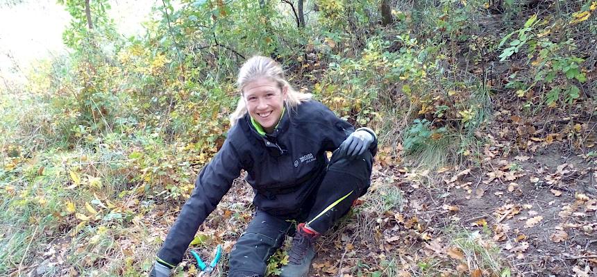 Frau sitzt am Waldboden
