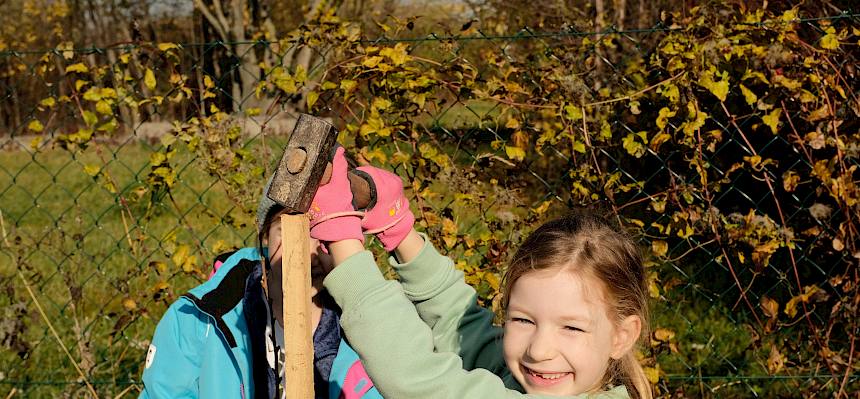 Schülerin schlägt Pflock ein