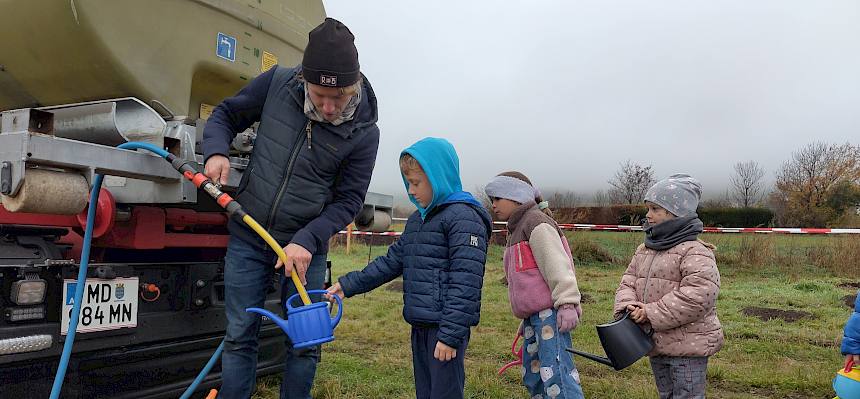 Naturpädagoge füllt Gießkannen auf