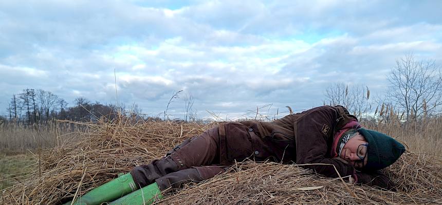 Biologin schläft auf Schilfhaufen