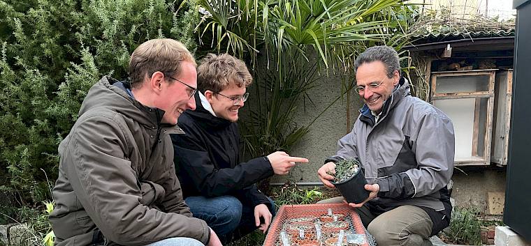 Biologe und Praktikant:innen vor Pflanzentopf