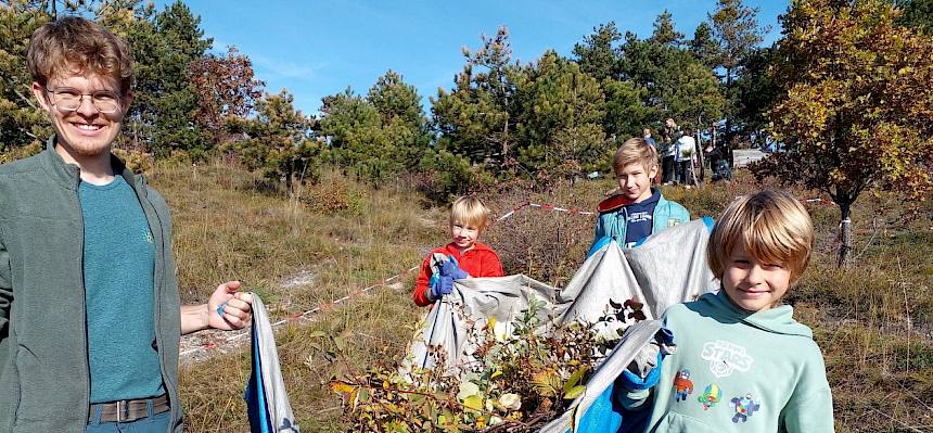 Praktikant hilft Kindern beim Tragen der Plane