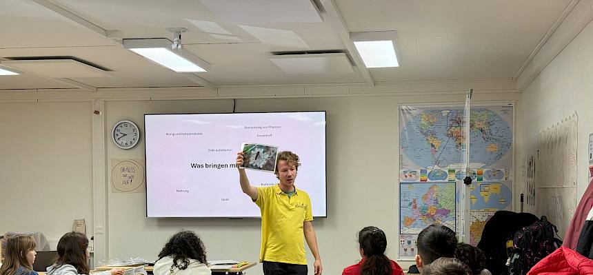 Naturpädagoge hält Folie mit Blume und Insekt hoch