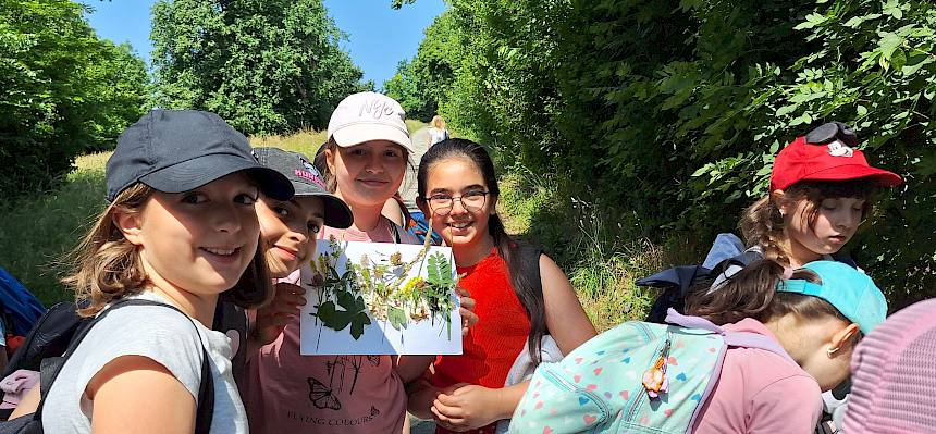 Mädchen zeigen Blatt Papier mit aufgeklebten Wiesenpflanzen