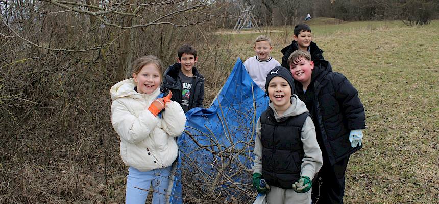 Kinder tragen Plane mit Schnittgut