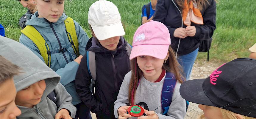 Schülerin zeigt Becherlupenfund Klassenkamerad:innen