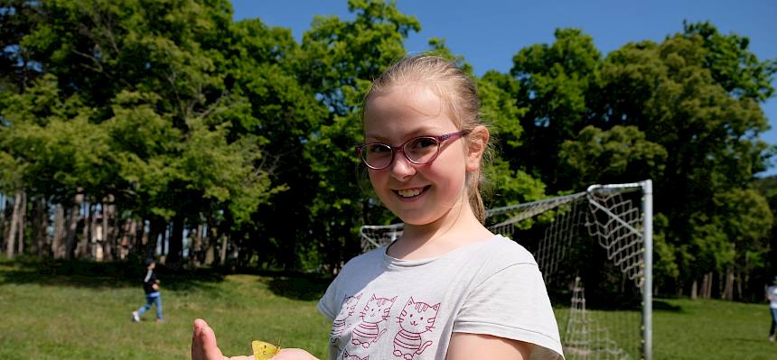 Kind mit Zironenfalter auf der Hand