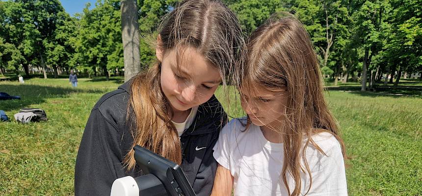 Kinder betrachten einen Wiesensalbei durch ein Binokular