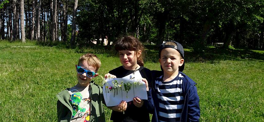 Kinder präsentieren ihr Wiesenklebebild