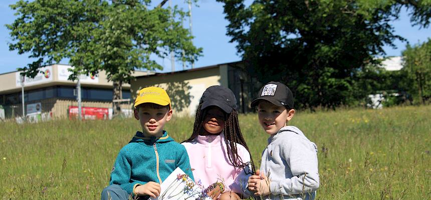 Kinder präsentieren ihr Wiesenklebebild