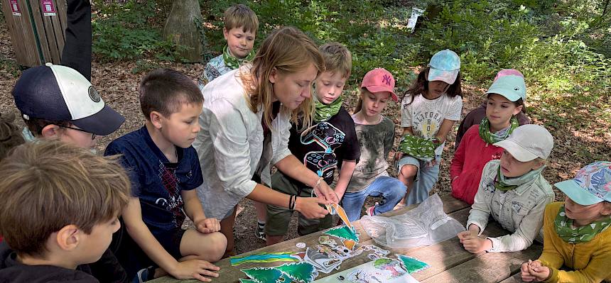 Naturvermitterin um Tisch mit Kindern