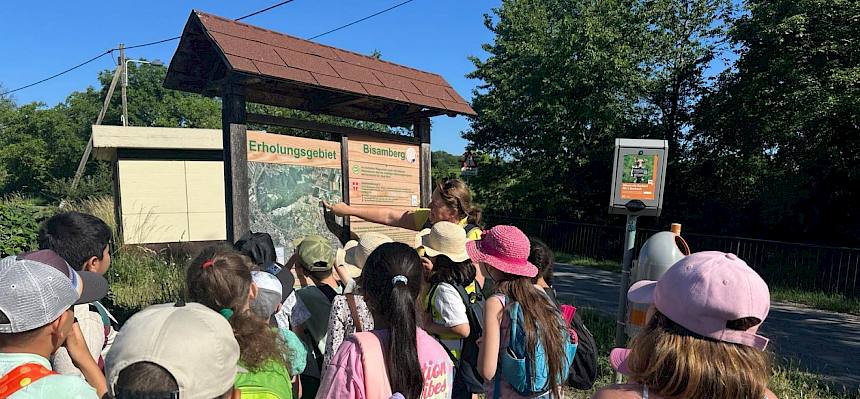 Naturvermittlerin und Kinder vor Bisamberg-Tafel
