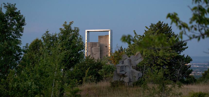 Blick über Trockenrasen auf Skulptur