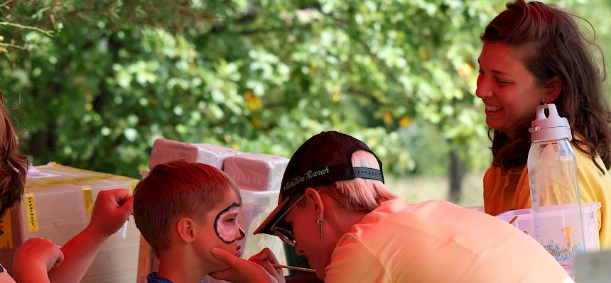 Naturvermittler:in malt mit Kinderschminke