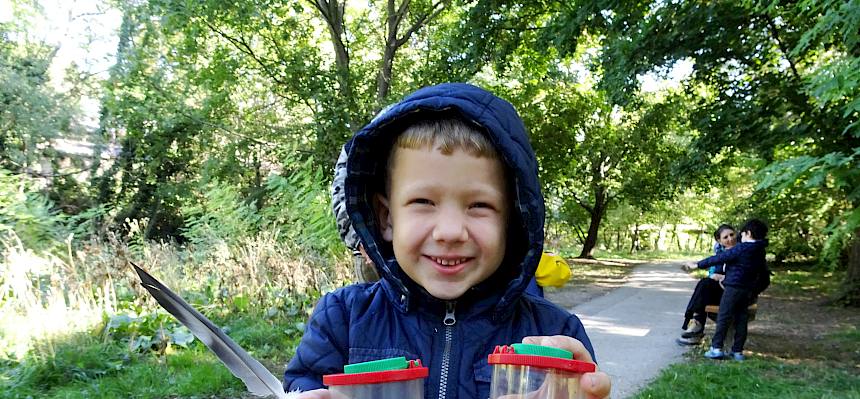 Kind mit Becherlupen und Feder