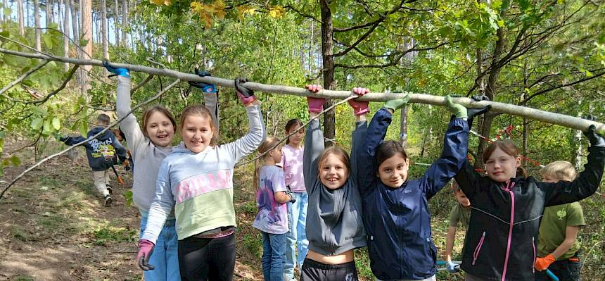 Schüler:innen halten Ast in die Höhe